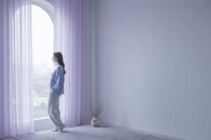 Mujer junto a una ventana en actitud reflexiva, ilustrando el sentirse sola en la pareja